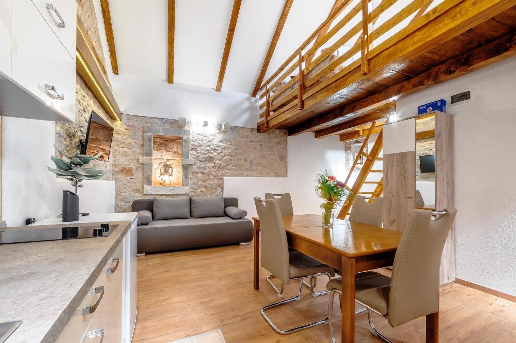 cocina y sala de estar con mesa de madera y sillas en Falcons Nest, en Šibenik