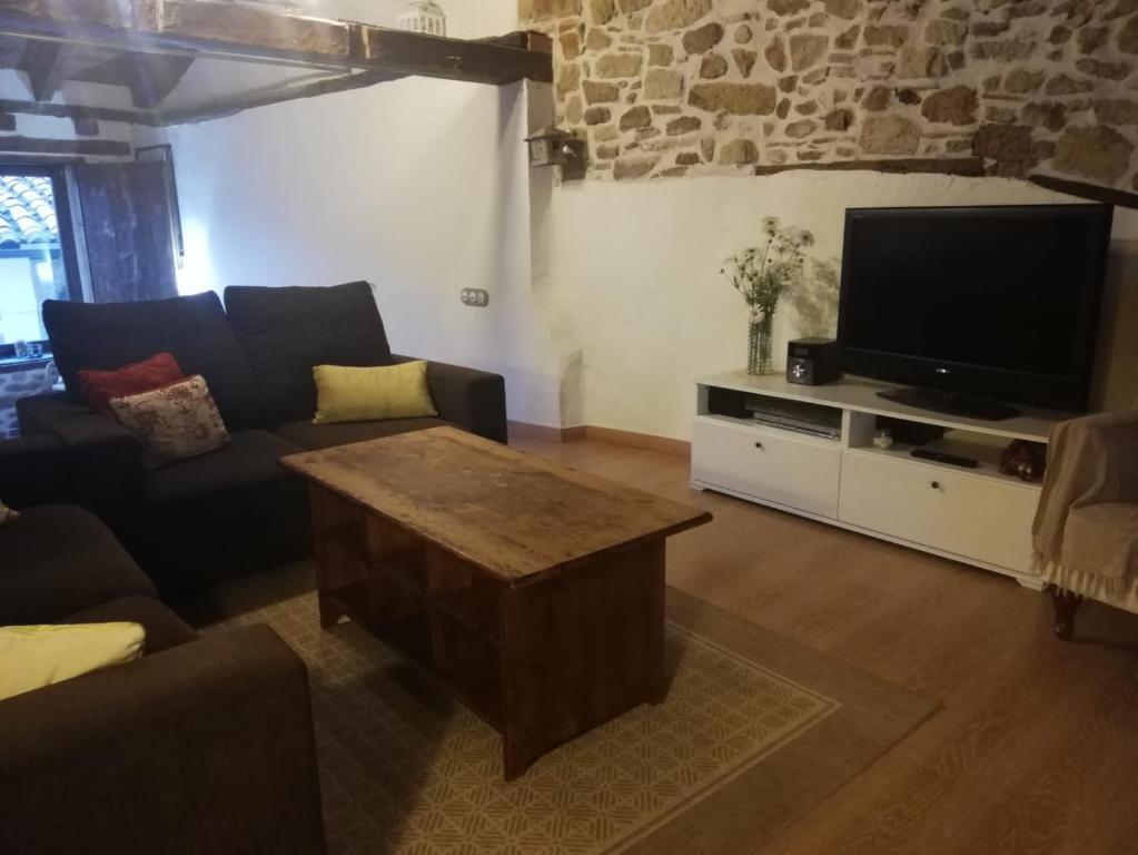 sala de estar con sofá y TV de pantalla plana en La Casita del Castillo, en Mora de Rubielos