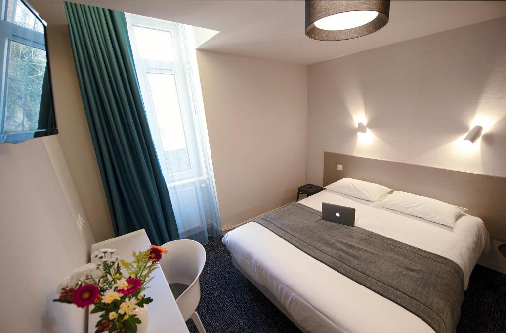 Una habitación de hotel con una cama y una computadora portátil encima. en Hôtel Du Port, en Morlaix