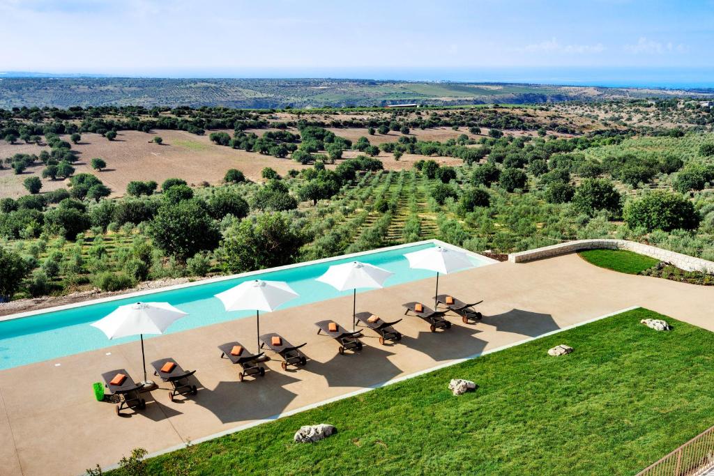 an aerial view of a pool with chairs and umbrellas at Relais Chiaramonte in Ragusa