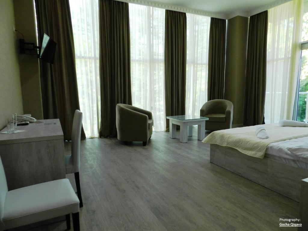 a hotel room with a bed and chairs and windows at Resort Martvili in Martvili