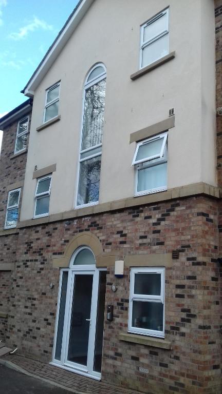 uma casa branca com janelas e um edifício de tijolos em 9 Column Mews em Alnwick