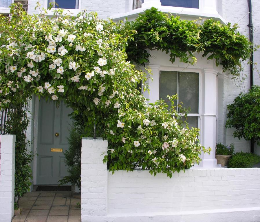 eine Haustür eines Hauses mit weißen Blumen in der Unterkunft Hurlingham Bed and Breakfast in London