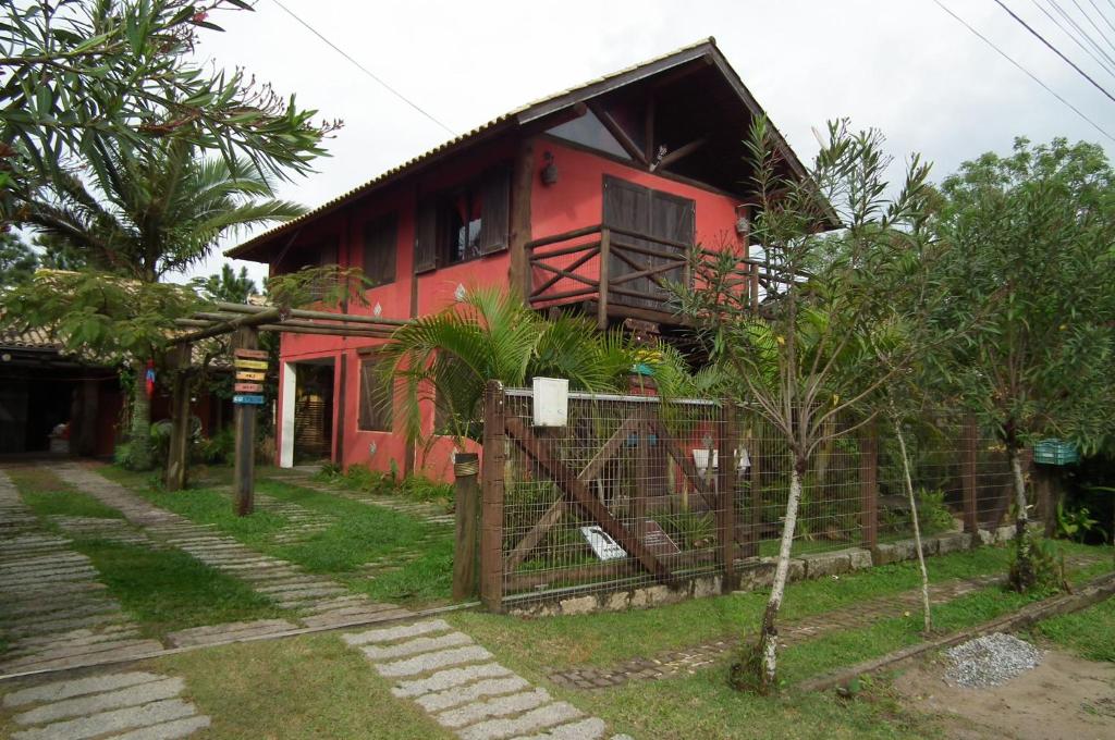 una casa roja con una valla delante en Cabanas Aconchegantes próximas ao mar, en Garopaba