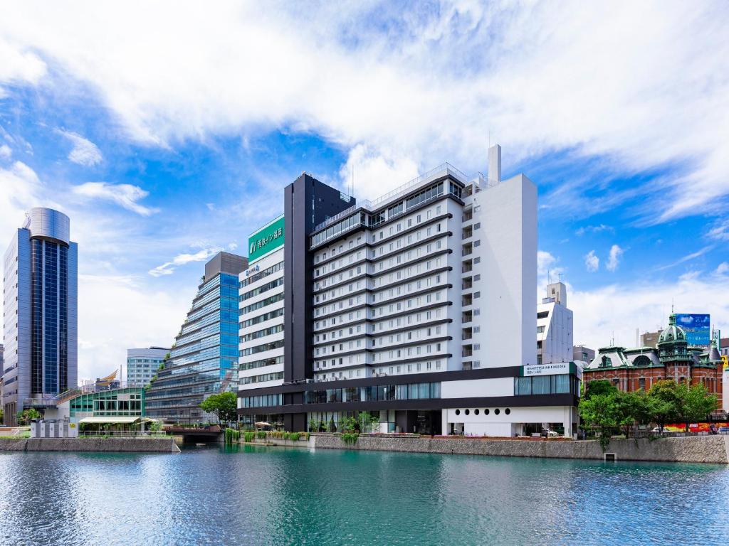 un edificio en una ciudad junto a un cuerpo de agua en Nishitetsu Inn Fukuoka en Fukuoka