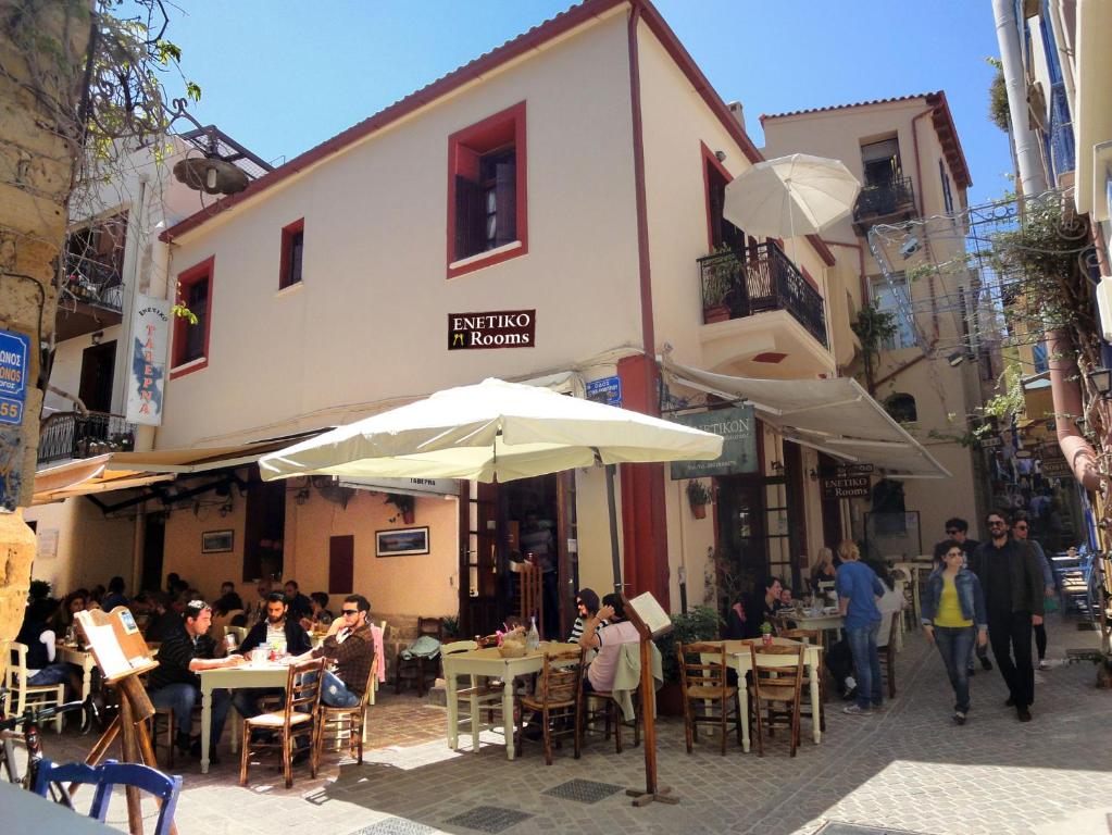 a group of people sitting at tables outside a building at Enetiko Rooms in Chania Town