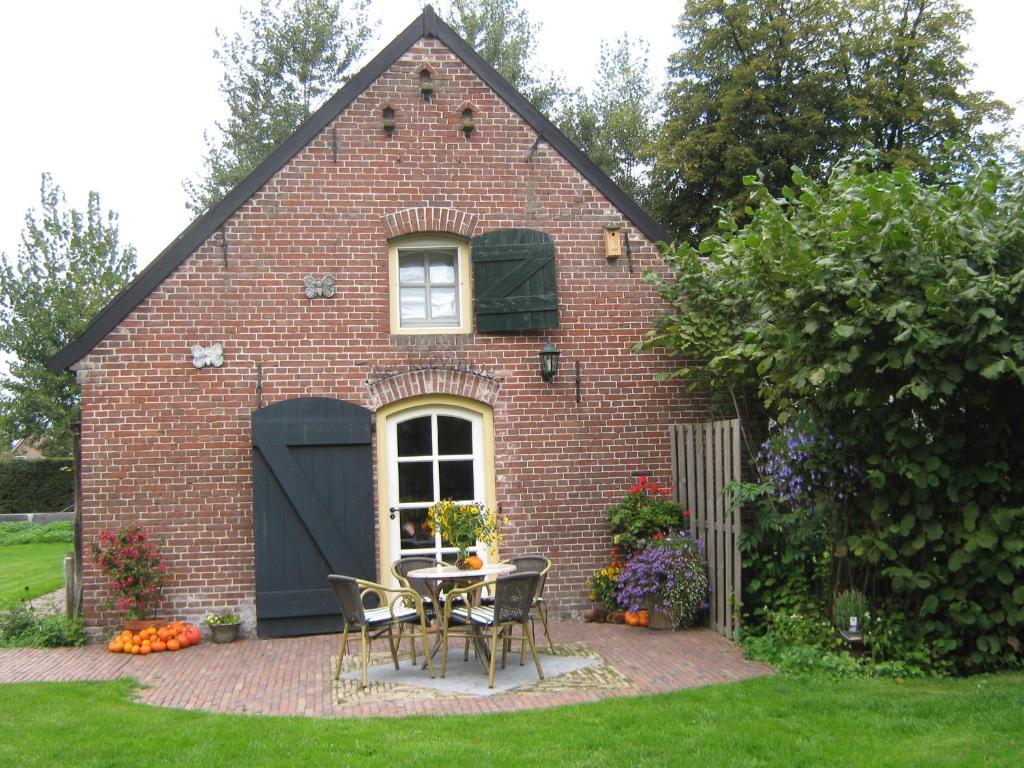 een stenen huis met een tafel en stoelen in de tuin bij De Hopbel & Het Koevinkje in Liempde