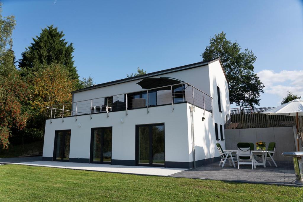 une maison blanche avec une terrasse et une pelouse dans l'établissement Villa WallAnn, à Morbach