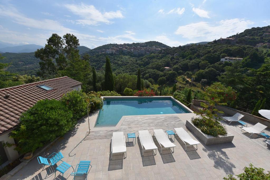 a swimming pool with chairs and a view of a mountain at Appart'hotel Fior Di Ribba in Sartène