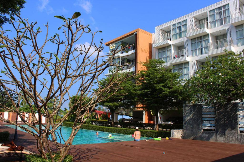 a person in a swimming pool in front of a building at At Sea Condo in Klong Muang Beach