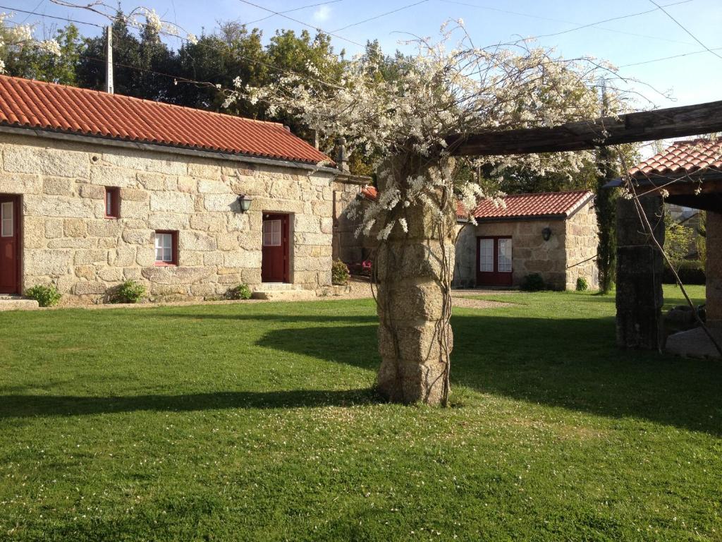 a tree in a yard next to a building at Quinta da Fonte Arcada in Paço de Sousa