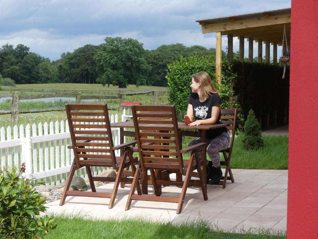 Eine Frau, die an einem Tisch mit zwei Stühlen sitzt. in der Unterkunft Parkland-Haus Dalwitz in Walkendorf