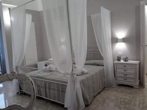 ein weißes Schlafzimmer mit einem Bett mit Vorhängen und einer Kommode in der Unterkunft Palazzo Mosca in Sannicola