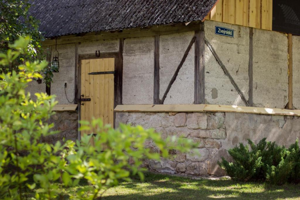 un edificio con puerta de madera y pared de piedra en Lauku māja "Zvejnieki" en Ķegums