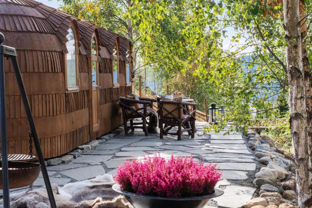 StrandlykkjaKonglehytta的庭院配有桌子和粉红色的鲜花