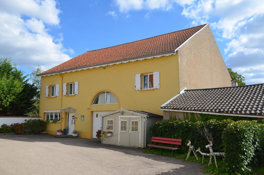 una casa amarilla con un banco delante en Gîte Brin de Campagne, en Vaucremont
