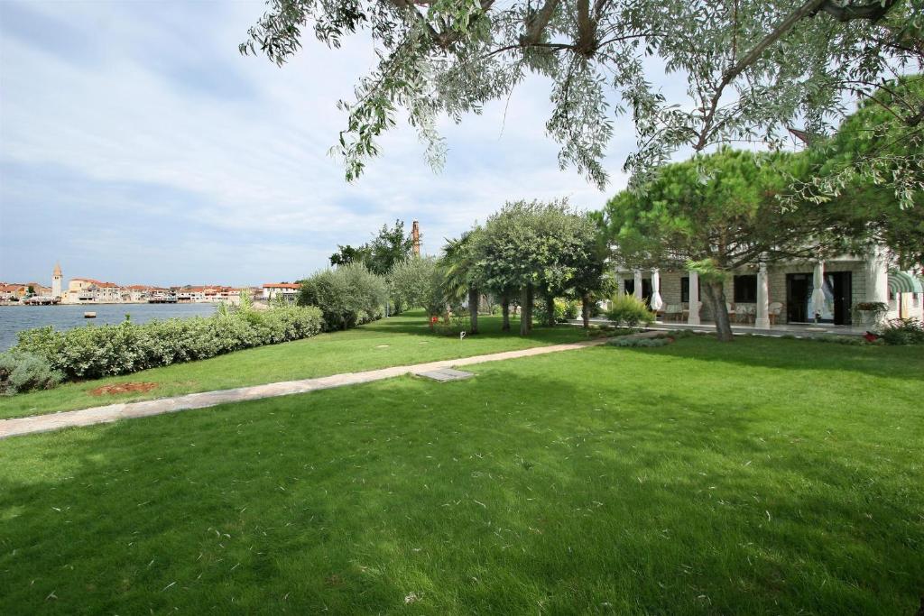 une maison avec une cour herbeuse à côté de l'eau dans l'établissement Apartments Bella Vista, à Umag