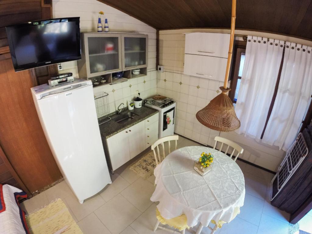 a small kitchen with a table and a refrigerator at Kitnet e Suite Morada Aguiar - Chalé in Abraão