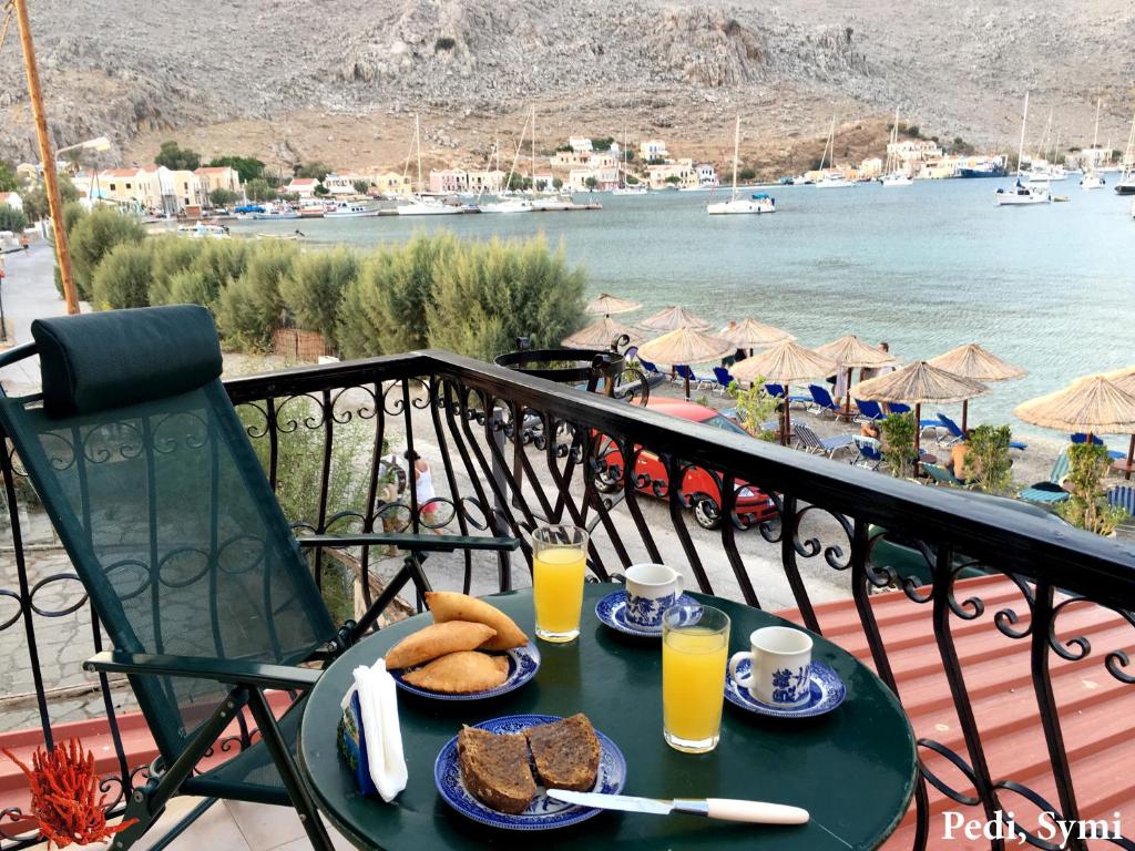 a table with bread and orange juice on a balcony at Korali in Symi