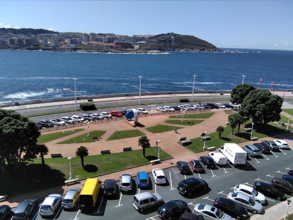 un parking avec de nombreuses voitures garées à côté de l'océan dans l'établissement Primera linea. Vistas al MAR, à La Corogne