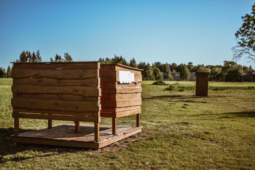 a wooden beehive sitting in the middle of a field at Sunny Nights Homestead Rustic House in Gataučiai