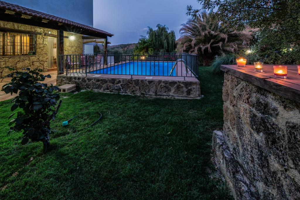 un patio trasero con piscina y pared de piedra en La Ventilla, en Arbuniel