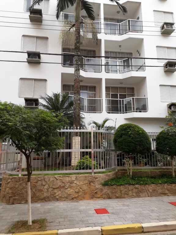 un edificio blanco con una palmera delante en Condomínio Praia de Marrakesch, en Guarujá