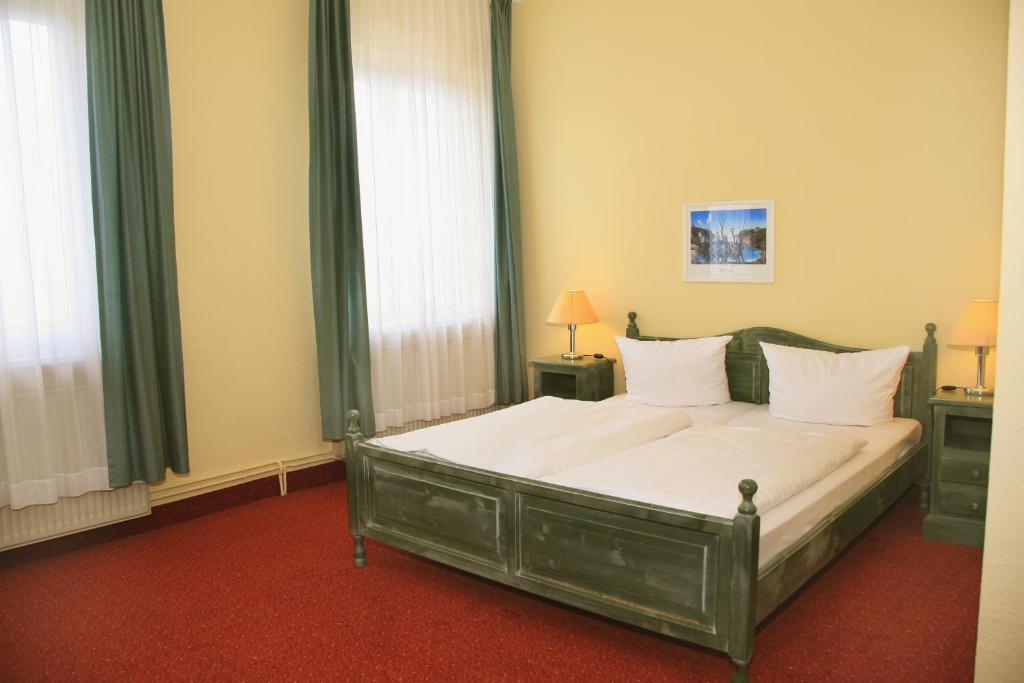 a bedroom with a bed with white sheets and windows at Hotel See-Eck in Heringsdorf