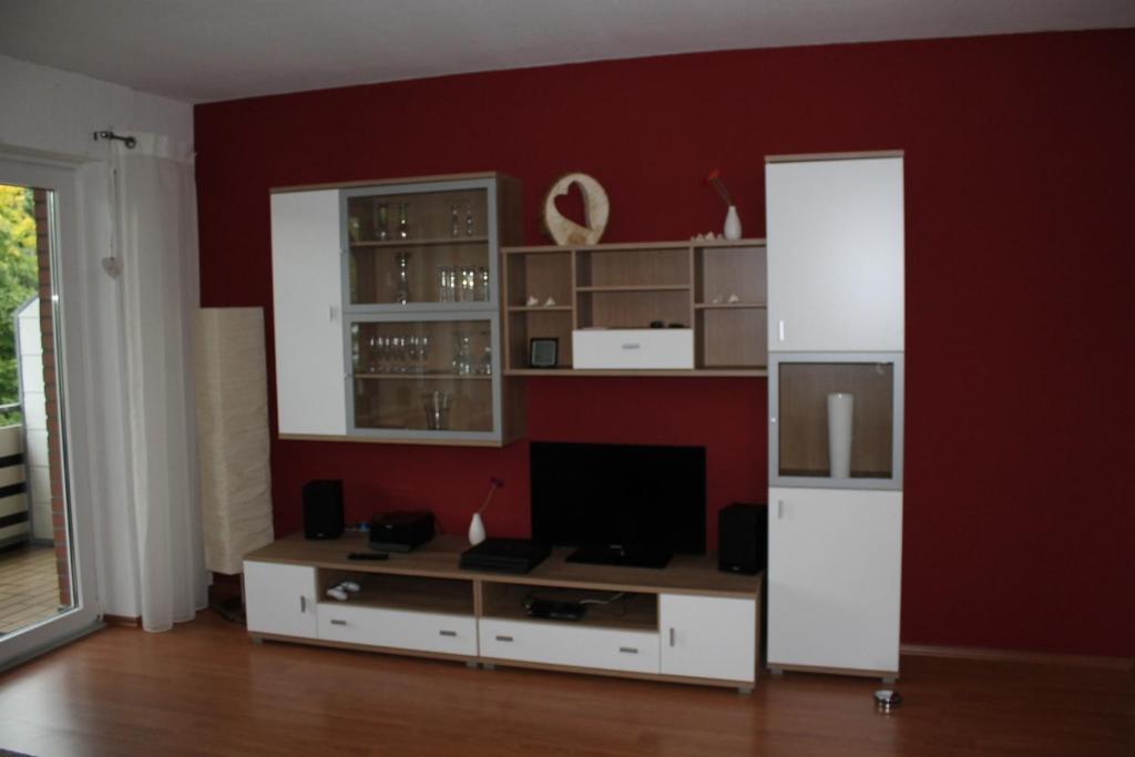 a living room with a white entertainment center and a red wall at Ferienwohnung Baum in Winterberg in Winterberg