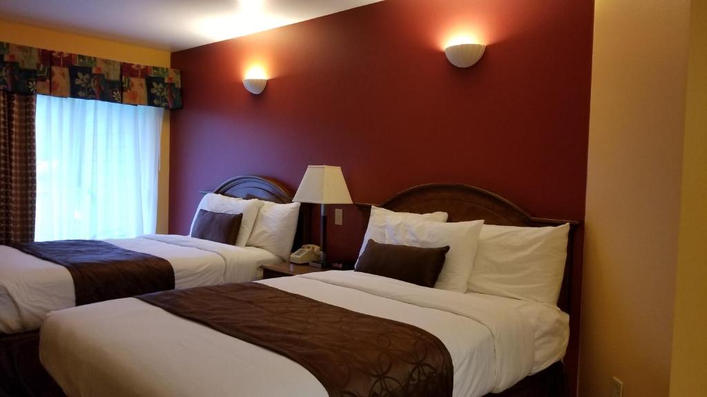 two beds in a hotel room with red walls at Dew Drop Inn in Forks