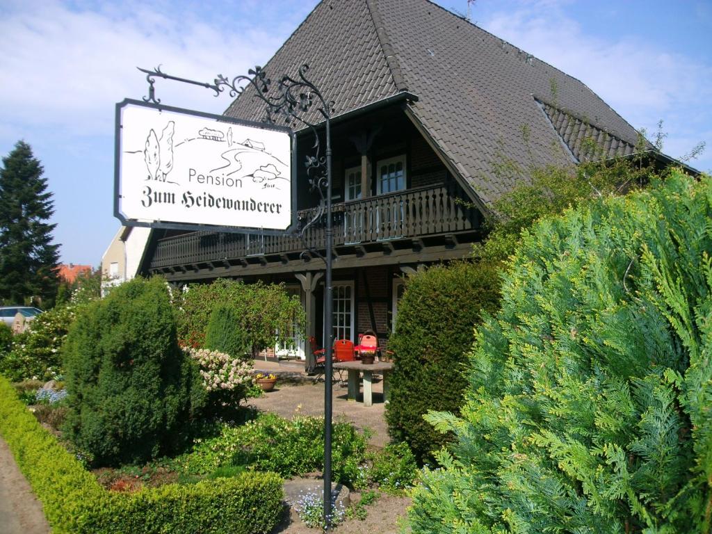 un panneau devant une maison avec un bâtiment dans l'établissement Landhaus Zum Heidewanderer, à Bad Bevensen