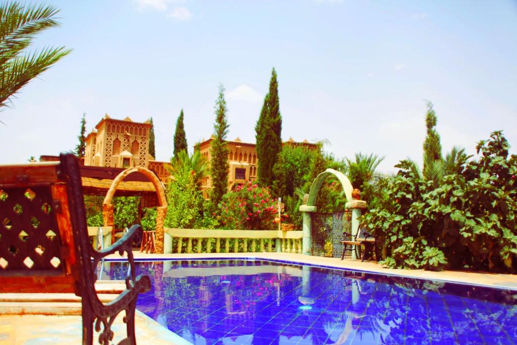 a swimming pool with a bench next to a house at Auberge Kasbah Tiriguioute in Skoura