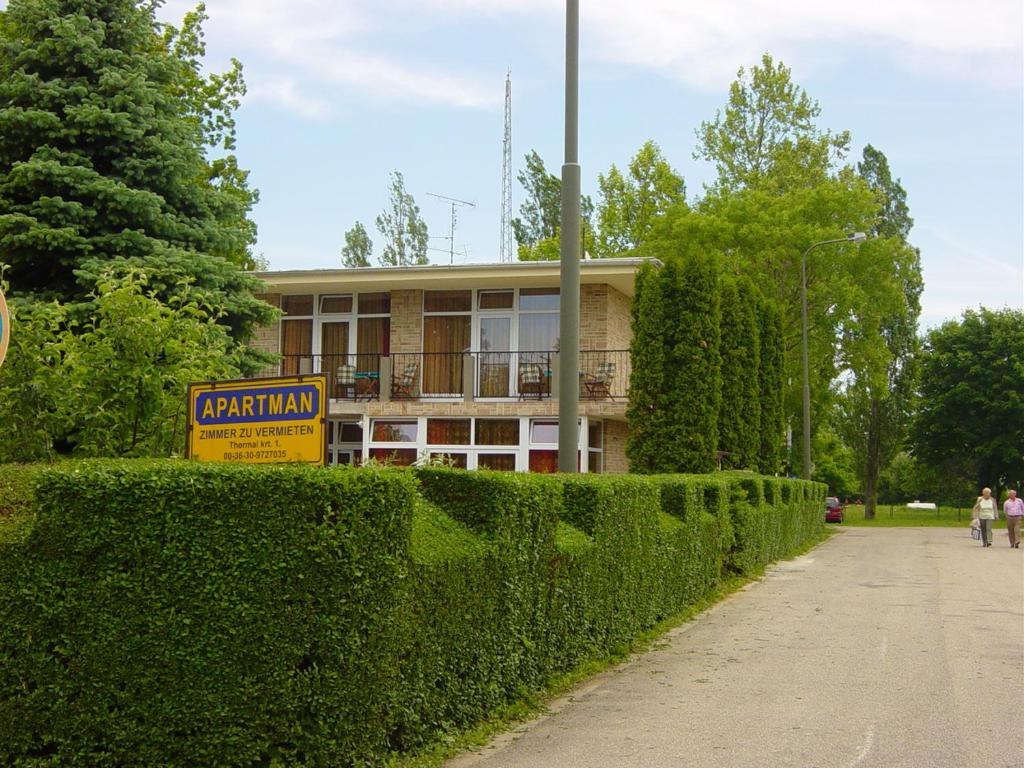 a building with a sign in front of a hedge at Apartman Danka in Bük