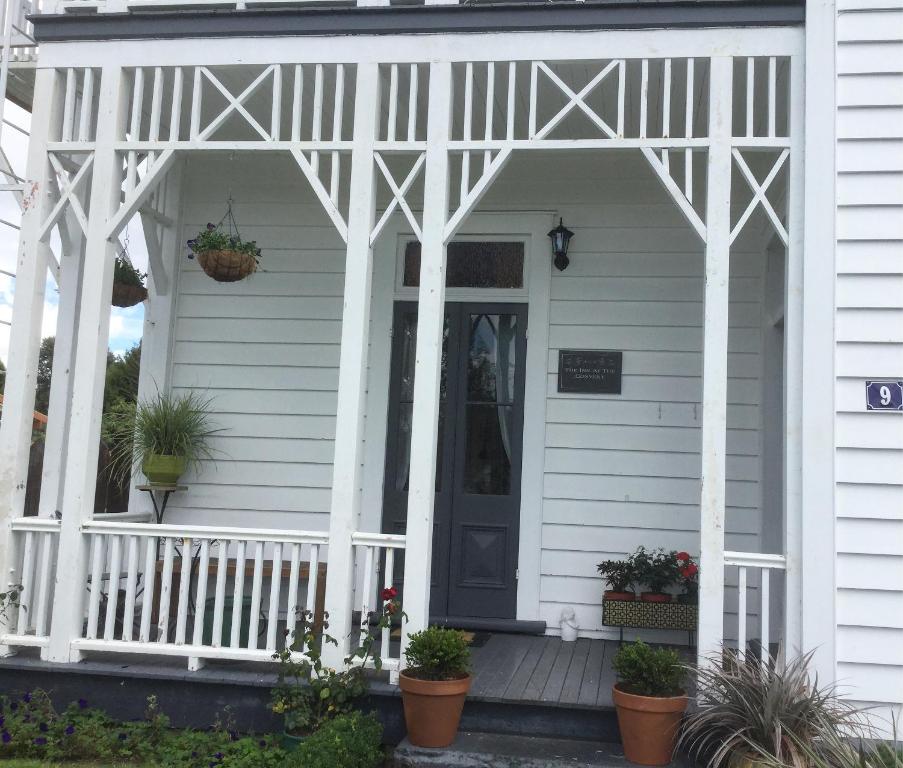 a white house with a porch with potted plants at The Inn At The Convent in Taumarunui