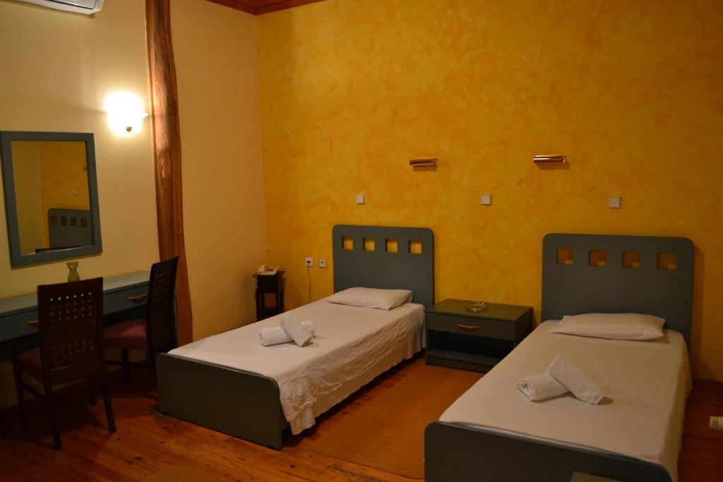 Habitación con 2 camas, mesa y espejo. en Hotel Koukouli en Souflíon