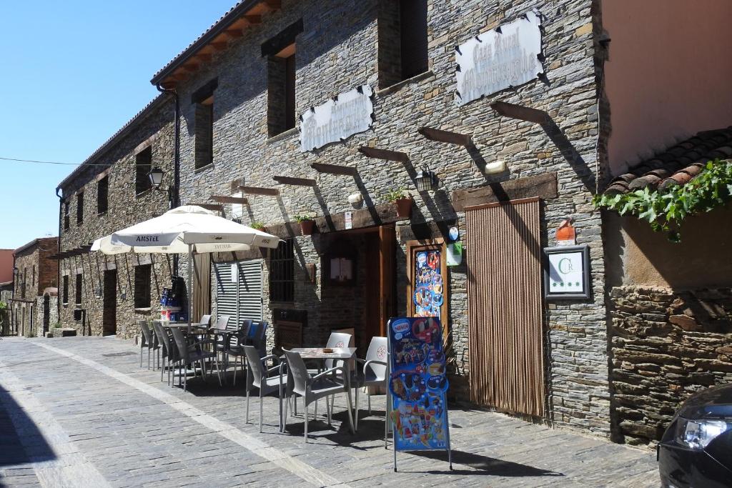 um edifício de tijolos com mesas e cadeiras e um guarda-sol em Casa Rural Monfragüe em Villarreal de San Carlos