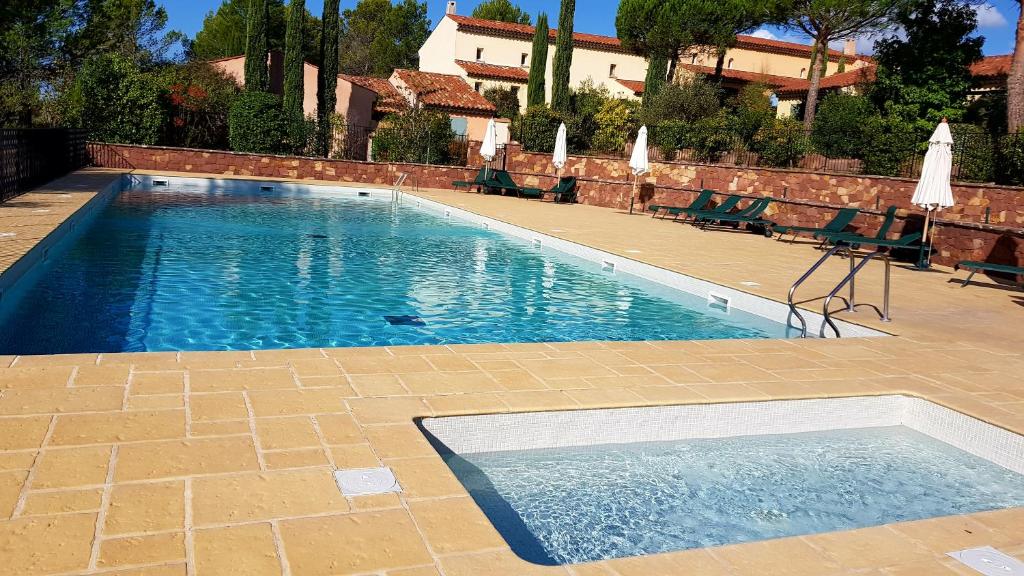 een zwembad met stoelen en parasols op een patio bij Villa au golf de St-Endréol in La Motte