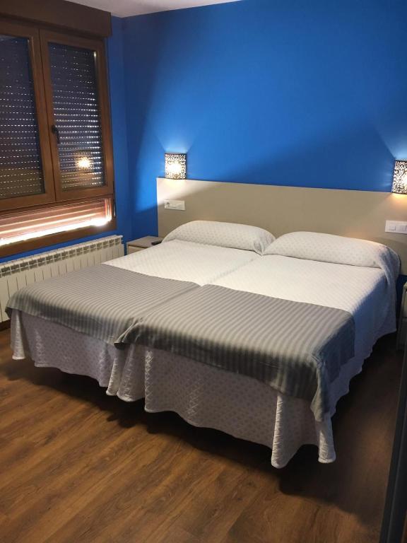 1 dormitorio con 2 camas y pared azul en Narcea Turismo Real, en Cangas del Narcea