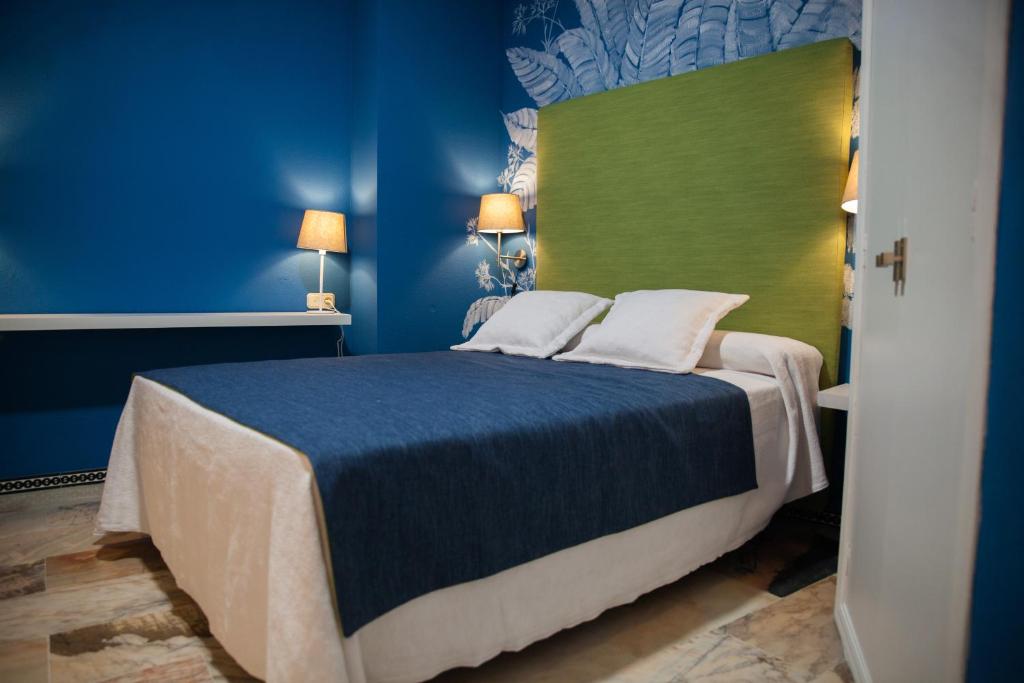 een blauwe slaapkamer met een bed met een groen hoofdeinde bij Ritual Sevilla Suite Alameda 5 in Sevilla