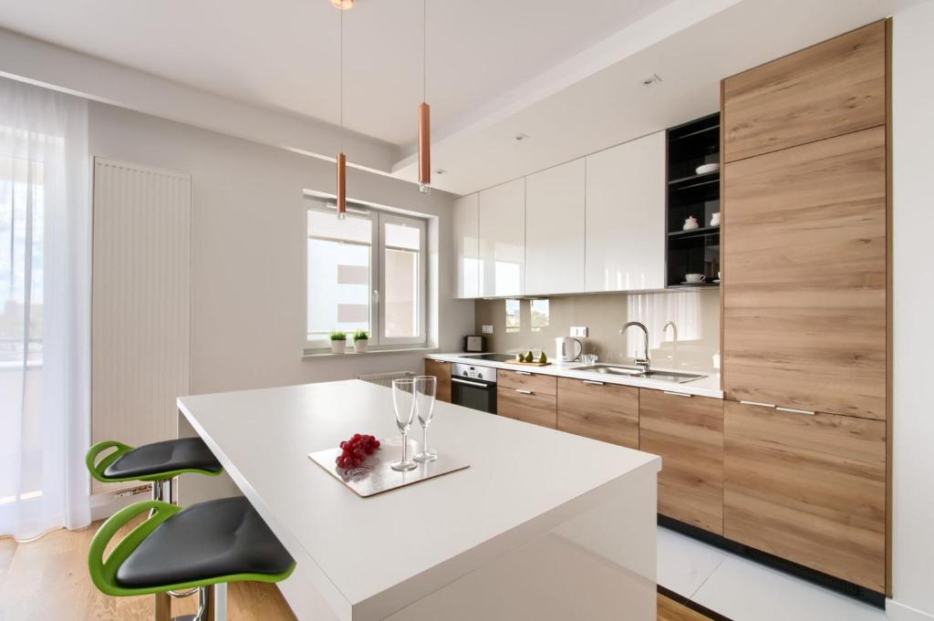 cocina con encimera blanca y armarios de madera en P&O Apartments Mokotów, en Varsovia