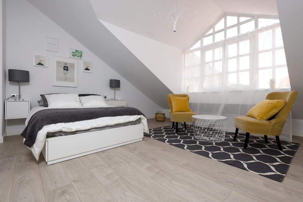 a white bedroom with a bed and two chairs at Maria Pita in A Coruña