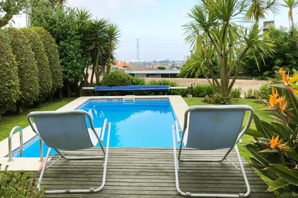 dwa krzesła siedzące obok basenu w obiekcie HOMEinLAND of TERROSO - Privat Pool, Grill & Seaview w mieście Póvoa de Varzim