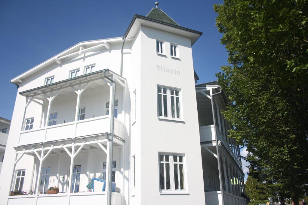 a white building with a clock tower on top at Meerblick Apartments Villa Vineta Göhren in Göhren