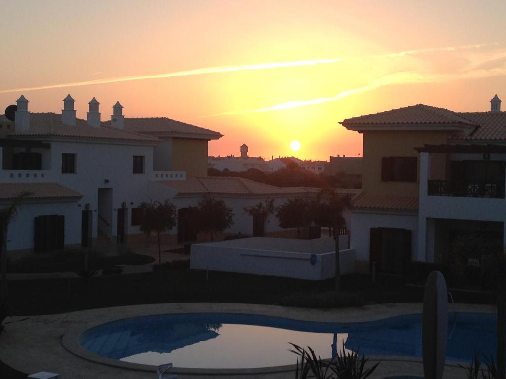 a sunset from the balcony of a house with a pool at Sagres Time Apartamentos in Sagres