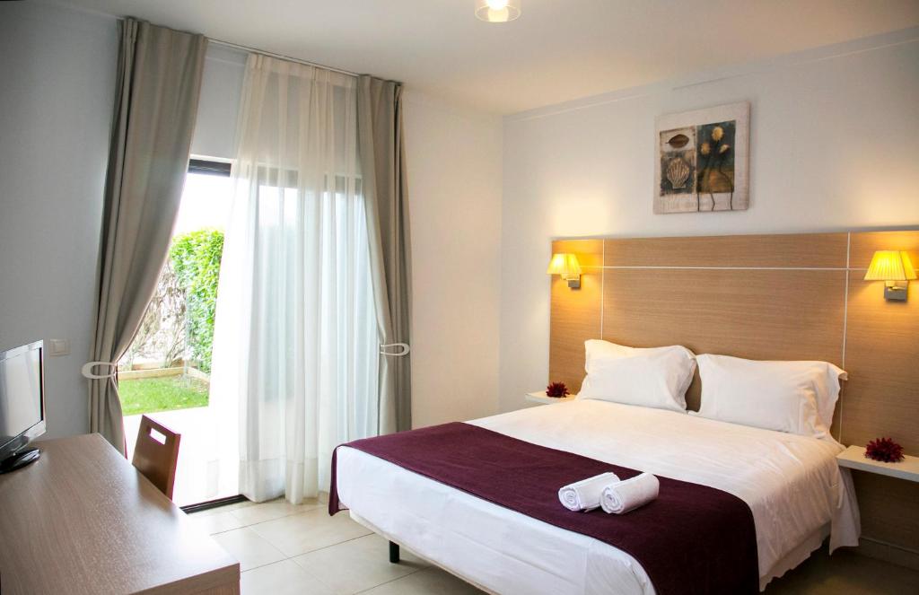 a hotel room with a large bed and a window at Sagres Time Apartamentos in Sagres