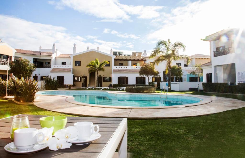 a table with cups and saucers next to a pool at Sagres Time Apartamentos in Sagres