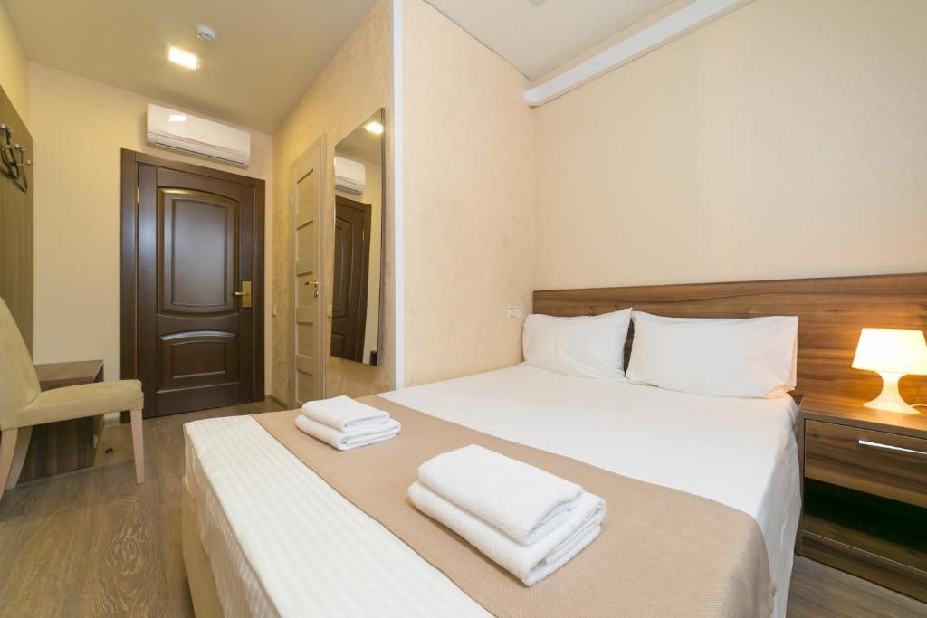 a bedroom with a white bed with two towels on it at Boutique Hotel on Mukomolniy in Moscow