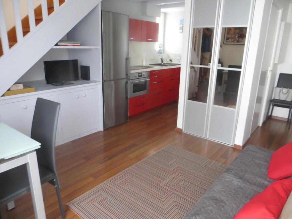 a kitchen with red cabinets and a kitchen with a table at résidence Biak Bat in Ciboure