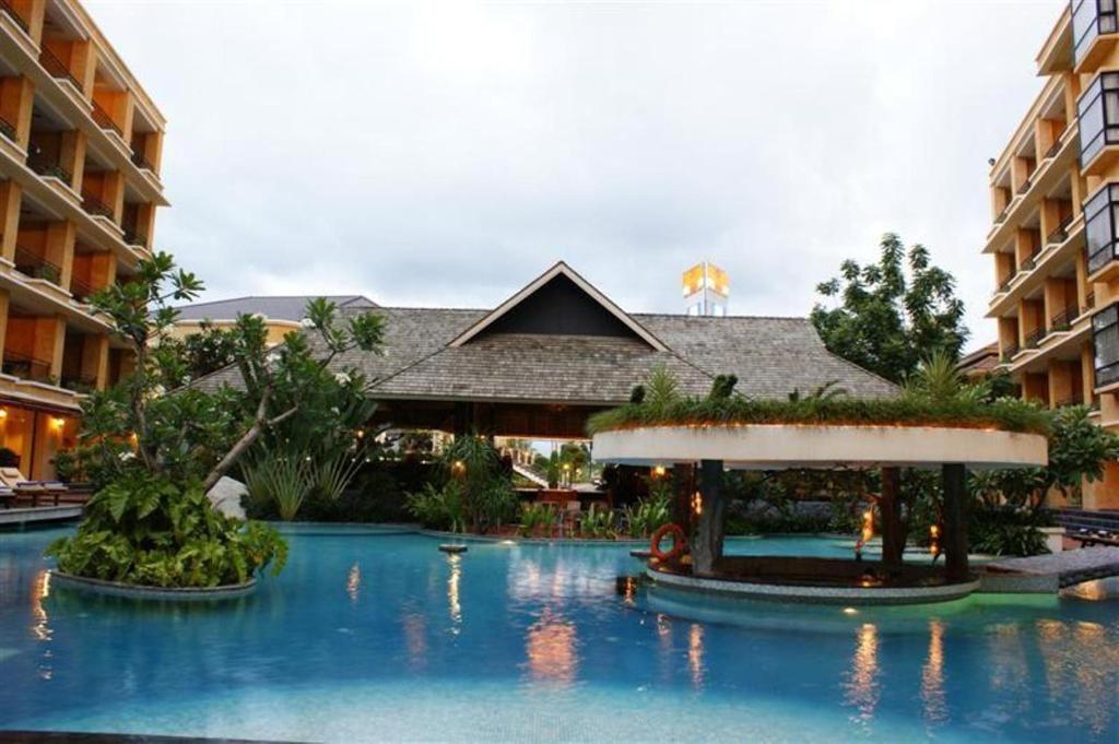 a resort with a swimming pool with trees and buildings at LK Mantra Pura Resort in Pattaya