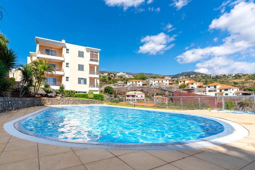 uma piscina numa villa com um edifício ao fundo em Zeza´s apartament na Calheta